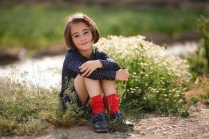 bambina seduta nel campo della natura che indossa un bel vestito foto