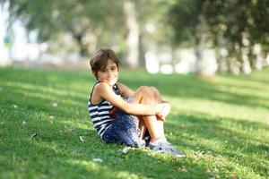 bambina, otto anni, seduta sull'erba all'aperto. foto