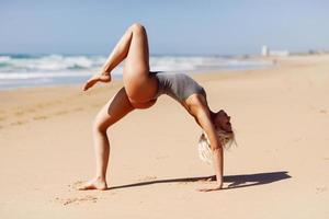 donna bionda caucasica che pratica yoga in spiaggia foto