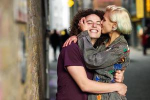 giovane donna che bacia il suo ragazzo in fondo urbano su una tipica strada londinese foto