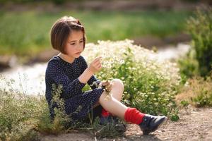 bambina seduta nel campo della natura che indossa un bel vestito foto