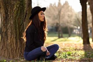 donna premurosa seduta da sola all'aperto con indosso un cappello