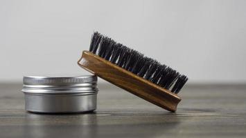 pennello da barba e barattolo di cera per barba e baffi su un tavolo di legno. accessori da barbiere. foto di alta qualità
