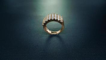 foto di un anello da donna che brilla su uno sfondo scuro