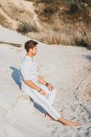 uomo in abiti leggeri siede nel deserto foto