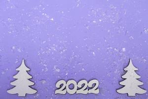 buon Natale e Felice Anno nuovo. manifesto festivo con un albero di natale, slitte su uno sfondo viola con luci. primo piano dello spazio della copia del nuovo anno 2022 foto