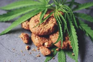 biscotti al cioccolato con foglia di cannabis - pianta di foglie di marijuana su sfondo scuro, concetto di erba naturale di cibo di cannabis foto