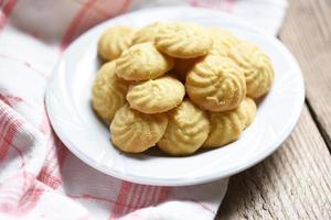 biscotti alla vaniglia su piatto bianco e fondo in legno, mini biscotti biscotti foto