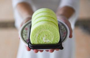 rotolo di torta sul piatto - donna servita rotolo di torta verde pandan con crema foto