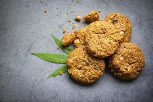 cannabis cibo natura erba concetto, biscotti al cioccolato con foglia di cannabis - pianta di foglie di marijuana su sfondo scuro foto