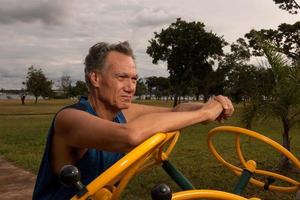 Senior uomo maturo che si allena in un parco fitness all'aperto a Parque das Garcas, Brasilia foto