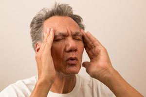 uomo anziano dolorante con mal di testa che si sfrega le tempie per trovare sollievo foto