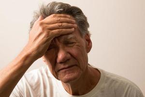 uomo anziano dolorante con mal di testa con la mano sulla fronte foto