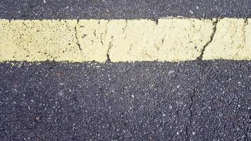 striscia orizzontale gialla su asfalto. dettaglio di una striscia gialla usurata nel tempo con una crepa, segnaletica stradale su asfalto. foto