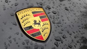 ucraina, kiev - 27 marzo 2020. logo porsche primo piano su un'auto nera con gocce di pioggia. emblema del cofano di un'auto sportiva. copia spazio, fotografia editoriale. mostra automobilistica tedesca sulla strada. foto