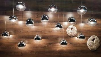 molte lampade rotonde vicino a una parete di legno marrone. luci rotonde all'interno. sfondo per il design. lampadine decorative.
