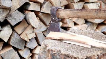 legna da ardere cippata per l'inverno per il riscaldamento. l'ascia è infilzata con una lama nel moncone. mannaia con manico in legno. raccolta in azienda. legna da ardere secca impilata in cataste per il riscaldamento di una casa foto