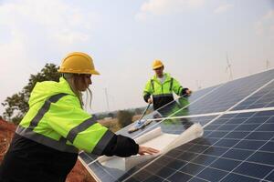 futuro elettrico produzione. maschio e femmina colleghi leggere disegno opera all'aperto di solare pannelli, verde energia, e rinnovo energia concetto foto