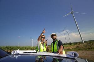 vento turbina ingegneri Lavorando su il tetto di auto a un' vento turbina campo, controllo e confrontando il planimetria e condizione di il turbina elettrico energia foto