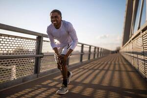 giovane afroamericano uomo è ferito mentre jogging. lui ha dolore nel ginocchio. foto