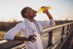 ritratto di giovane afroamericano uomo chi è potabile acqua e rilassante dopo jogging. foto