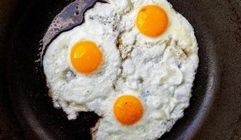 tre uova fritte ruspanti in una padella antiaderente calda foto