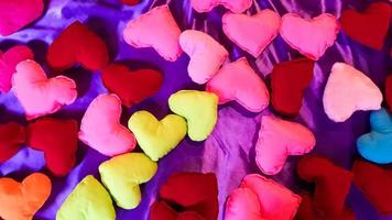 cuori di peluche multicolori e luminosi su uno sfondo di letto viola. il giorno di san valentino o il concetto di amore.