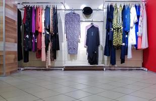 sfilata di moda di eleganti vestiti di lusso alla moda all'interno del negozio sui ganci. foto editoriale. lo shopping è una vacanza preferita per ragazze e donne.