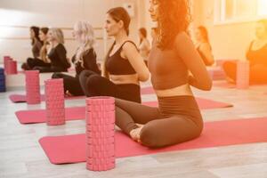 un' gruppo di sei atletico donne fare pilates o yoga su rosa stuoie nel davanti di un' finestra nel un' beige soffitta studio interno. lavoro di squadra, bene umore e salutare stile di vita concetto. foto