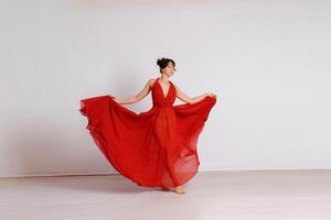 ballerino nel un' rosso volante vestire. donna ballerina danza su un' bianca studio sfondo foto