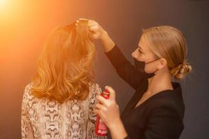 donne salone acconciatura. parrucchiere usi lacca per capelli su del cliente capelli nel salone, ritratto di Due bellissimo donne foto