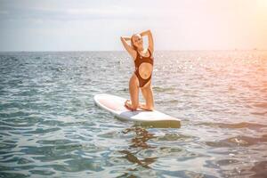 donna cenare mare. gli sport ragazza su un' tavola da surf nel il mare su un' soleggiato estate giorno. nel un' nero bagnarsi completo da uomo, lui si siede su un' sapa nel il mare. riposo su il mare. foto