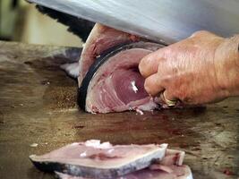 dettaglio di mano di un' pescivendolo chopping spadaccino a fresco pesce frutti di mare a ortigia siracusa sicilia pesce mercato Italia foto