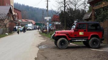 Ucraina, yaremche - 20 novembre 2019. una jeep wrangler 4.0i v6 suv rossa è parcheggiata su una strada rurale vicino a una casa in una piccola città dei Carpazi ucraini. escursioni in montagna giro in jeep. foto