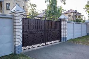 moderno privato in ferro battuto marrone grande cancello della casa. idee di design e decorazione per la casa. porta in ferro per recinzione cortile. facciata di una casa su una strada cittadina. foto