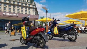 ucraina, kiev - 29 agosto 2020. sacco di ciclomotori parcheggiati con borse gialle con logo glovo vicino a mcdonald's. servizio di corriere che consegna la merce ordinata tramite un'applicazione mobile. fotografia editoriale. foto