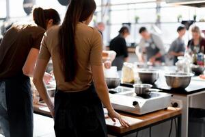 culinario classe. indietro Visualizza di il processi di cucinando. diverso irriconoscibile persone nel grigio grembiuli nel il cucina imparare per cucinare foto