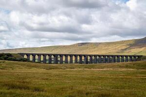 storico pietra viadotto nel lussureggiante campagna con rotolamento colline sotto un' nuvoloso cielo a ribblehead viadotto, yorkshire foto