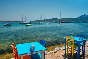 bar tavolo spiaggia nel Adamantas cittadina su milos isola con Egeo mare con Barche nel sfondo foto