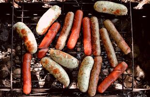 grigliato wurstel e salsiccia su il barbecue al di sopra di carboni foto