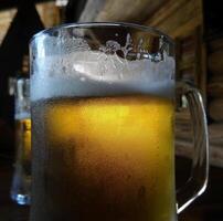 Due pinte di mestiere birra con schiuma su il bicchiere su il legna tavolo foto