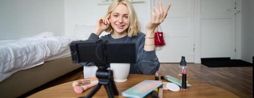 ritratto di giovane adolescenziale ragazza nel sua camera, registrazione un' video blog, quotidiano stile di vita per sociale media, Internet influencer pubblicità Prodotto in linea, parlando per il telecamera, seduta su il pavimento foto