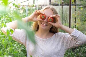sorridente agricoltura lavoratore Tenere pomodori al di sopra di occhi nel serra. fresco di stagione verdure raccolto. cibo produrre e coltivazione. sostenibile agricoltura foto