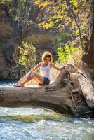 ragazza seduta su un' grande albero sopra il fiume foto