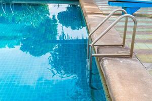 afferrare la scala delle barre nella piscina blu foto