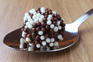 brigadeiro, brigadier, dolce al cioccolato tipico della cucina brasiliana ricoperto di particelle, su fondo in legno. foto