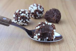 brigadeiro, brigadier, dolce al cioccolato tipico della cucina brasiliana ricoperto di particelle, su fondo in legno. foto