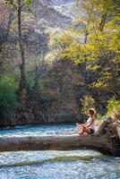 ragazza seduta su un' grande albero sopra il fiume foto