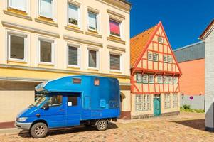 Flensburg, Germania - camper blu parcheggiato vicino a un edificio moderno e una vecchia casa in tradizionale stile tedesco, vista su una strada a Flensburg foto