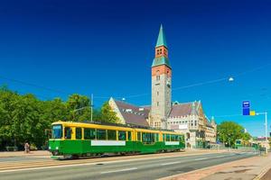 Vista di un tram cittadino a Helsinki e il vecchio edificio storico del Museo Nazionale della Finlandia con cielo azzurro sullo sfondo foto